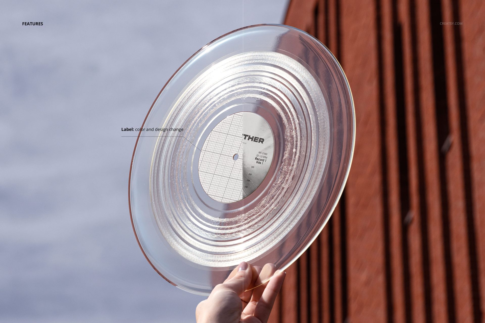 Transparent vinyl record mockup held up against the sky, with a brick building in the background and visible label.