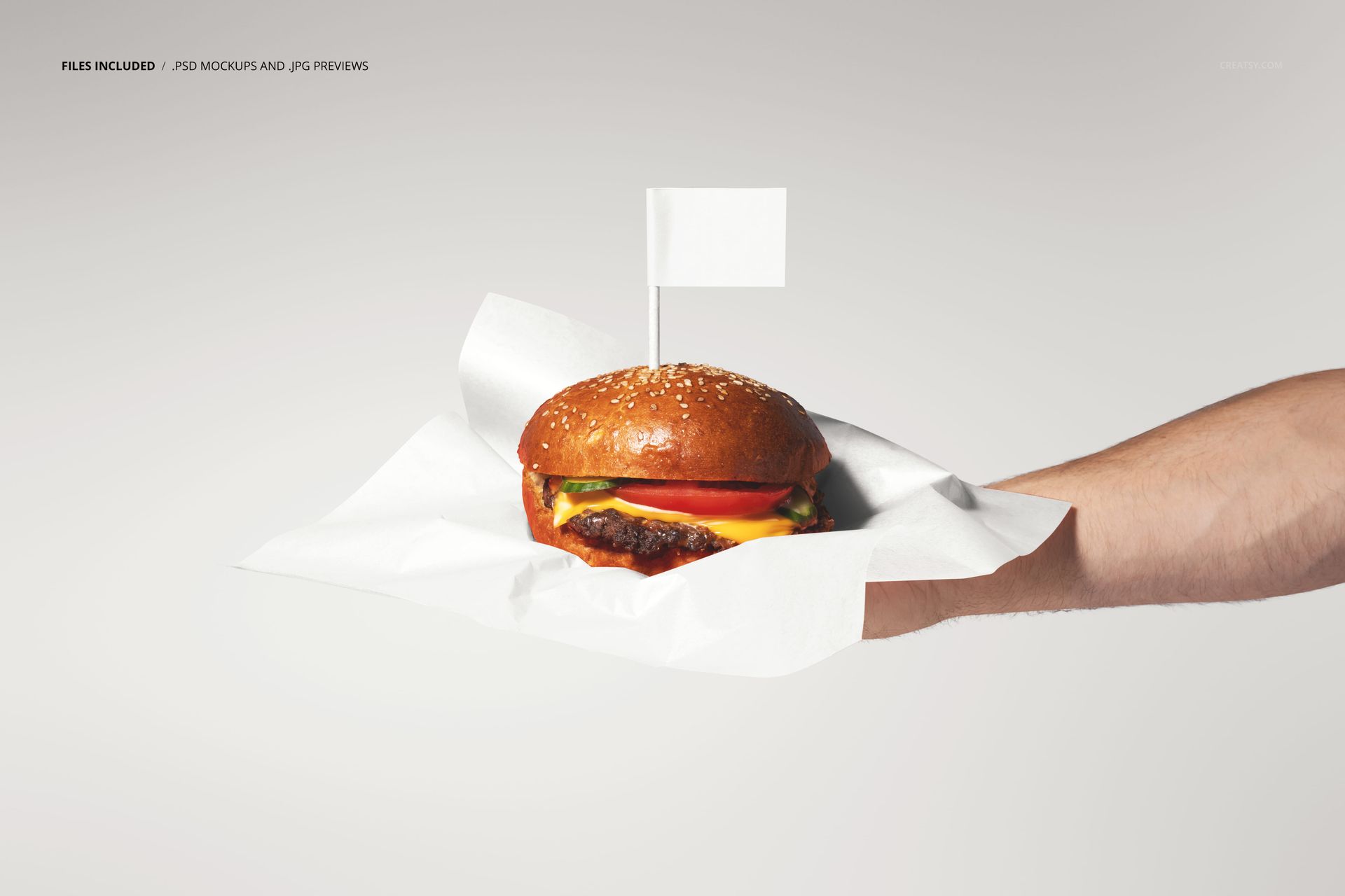 Burger with lettuce, tomato, and cheese served on white paper, held in a hand, PSD mockup scene.