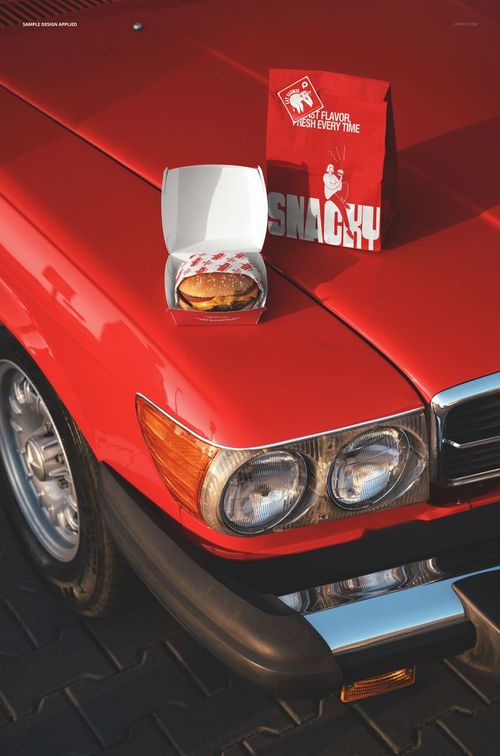 Burger packaging mockup featuring a red paper bag and open burger box placed on the hood of a classic red car.