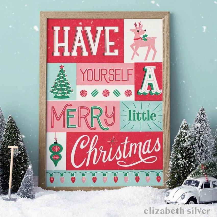 Christmas picture frame mockup featuring festive artwork with colorful text and illustrations, surrounded by snow and mini trees.