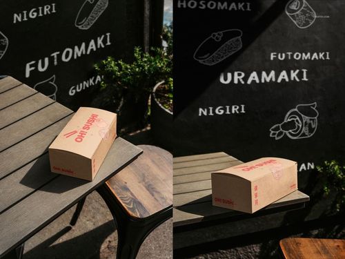 Cardboard takeaway box mockup on an outdoor wooden table with sunlight and chalkboard sushi menu in the background.