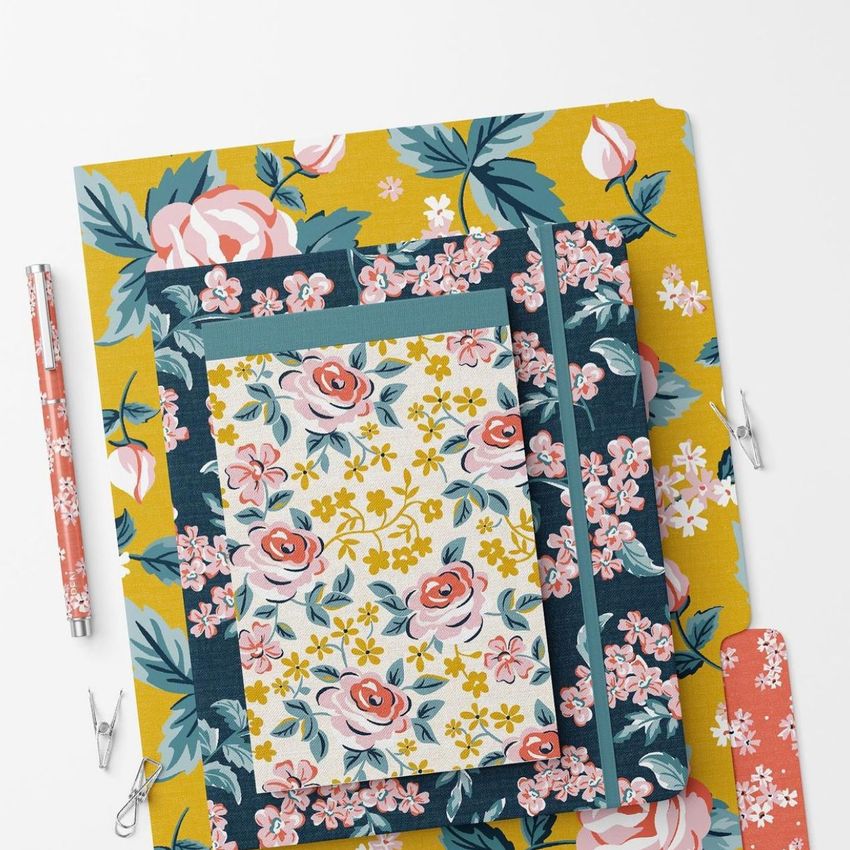 Stationery set mockup featuring notebooks and folders with colorful floral patterns on a white background, viewed from above.