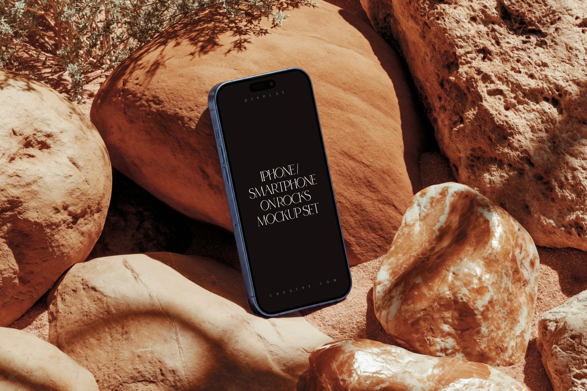 PSD mockup of an iPhone smartphone placed vertically on sunlit rocks with earthy tones and shadows.