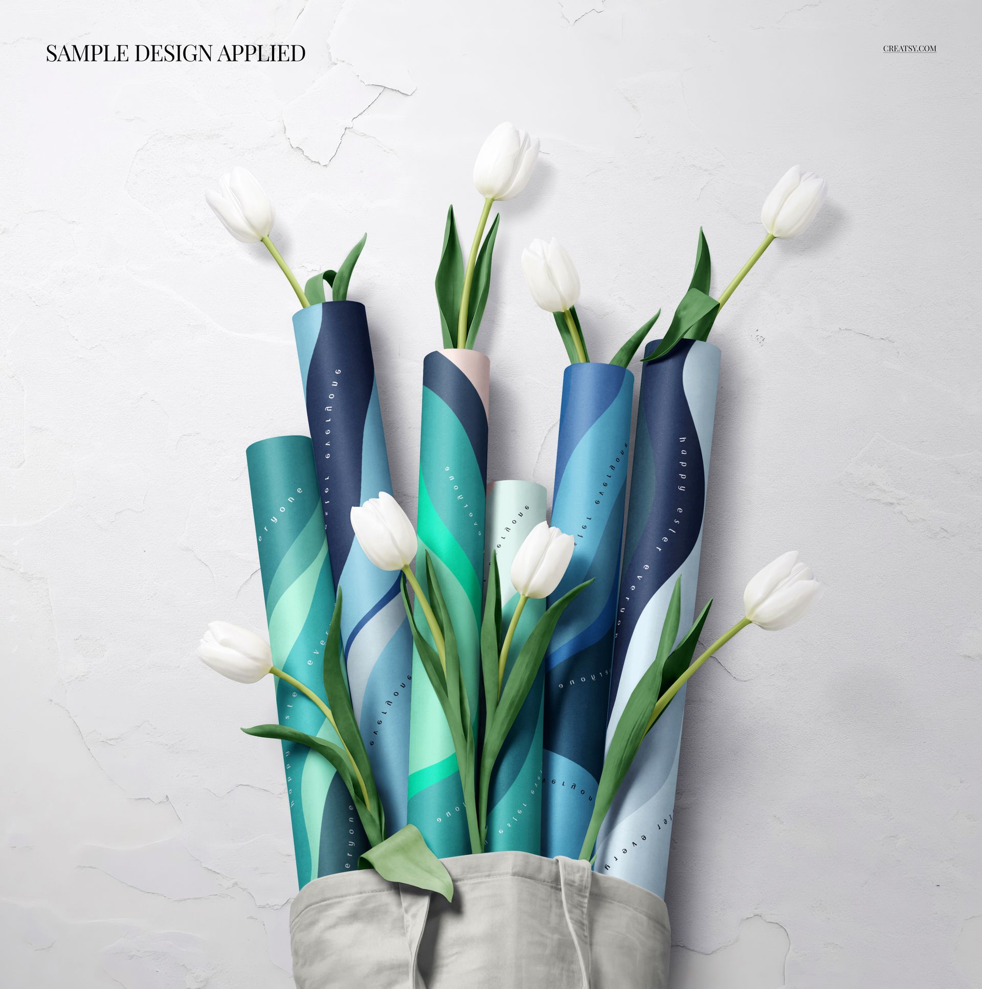Wrapping paper rolls in shades of blue and green arranged in a tote bag with white tulips, PSD mockup scene.