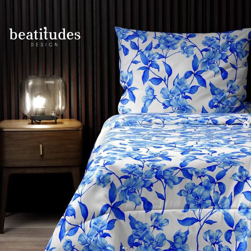 Microfiber comforter mockup featuring a blue floral pattern on a bed, with a matching pillow and a wooden nightstand with a lamp.