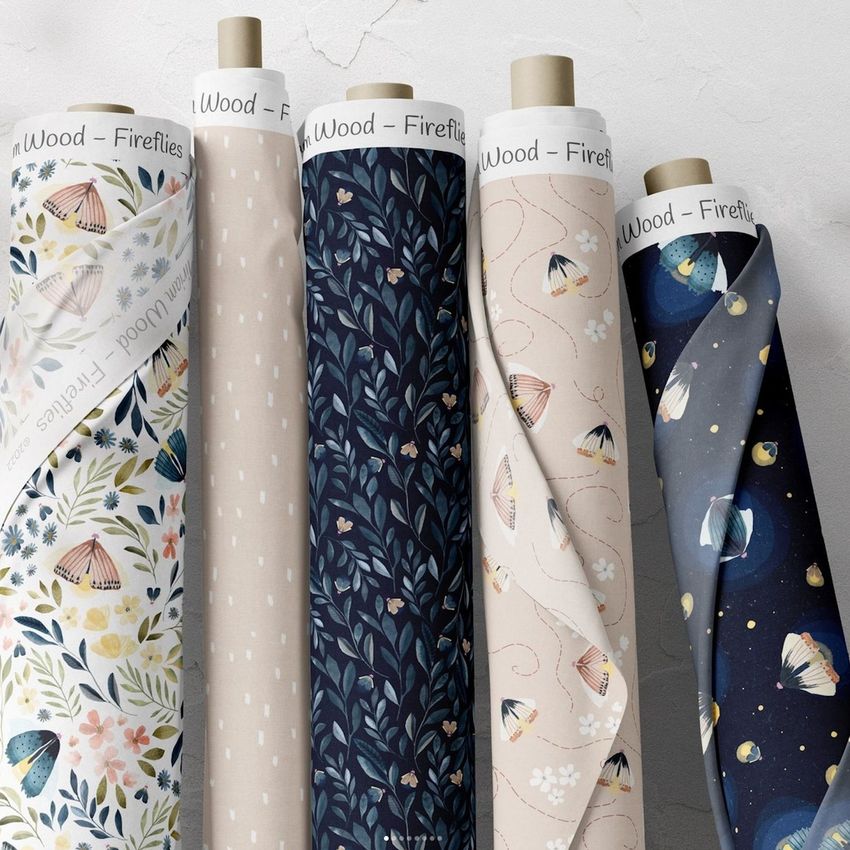 Fabric rolls mockup showing five upright rolls with various botanical and firefly-themed patterns in soft and dark colors.
