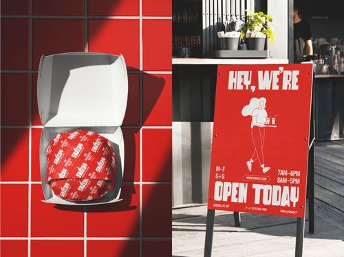 Fast food branding mockup showing a burger in a white box and a red promotional signboard outside a restaurant.