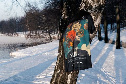 Bella Canvas 3001 t-shirt mockup featuring a bold design, displayed on a tree with snow and a frozen lake in the background.