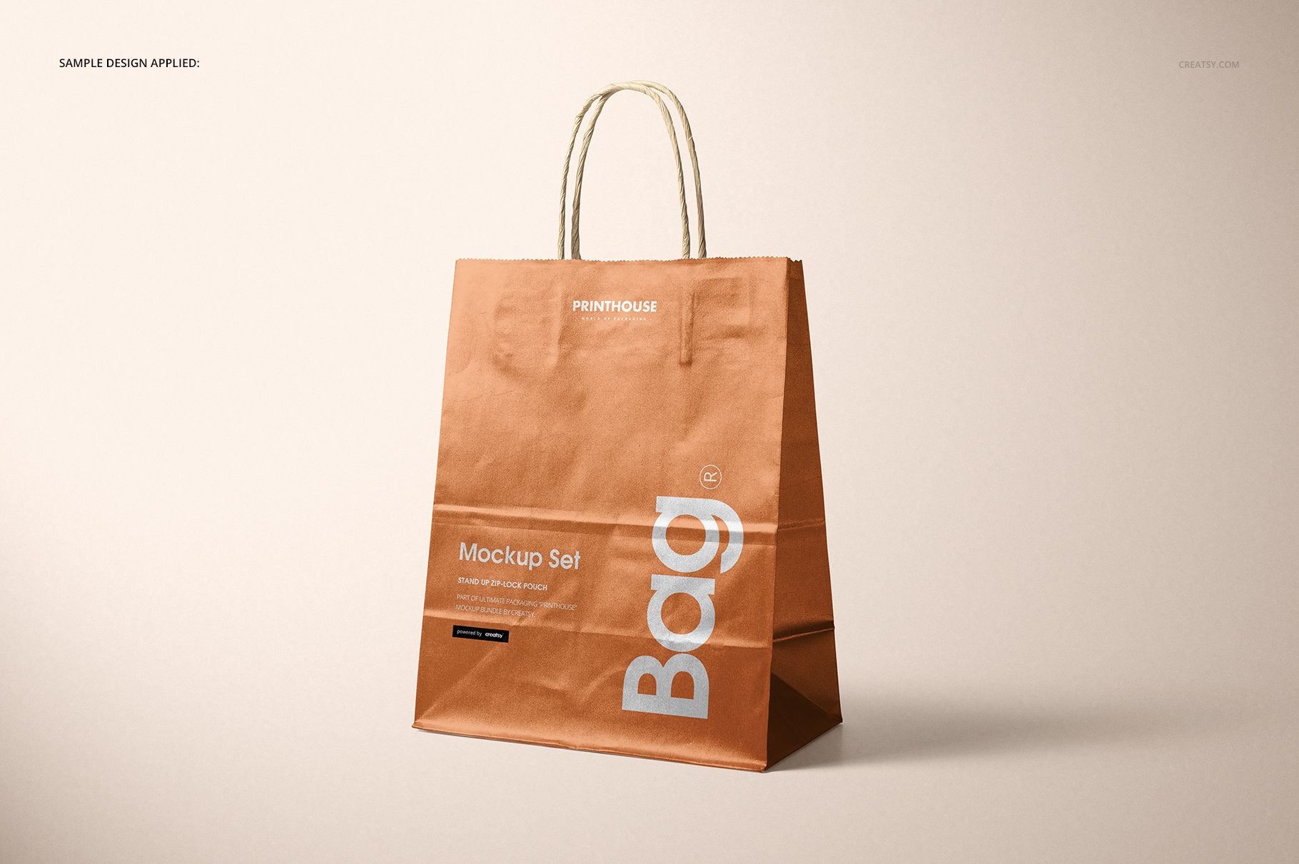 Metallic kraft paper shopping bag mockup shown upright with visible creases and printed text, beige backdrop.