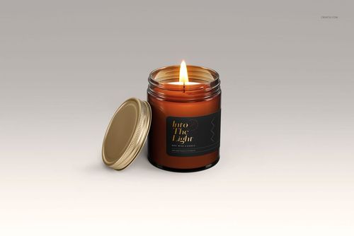 Lit amber glass candle jar with gold lid off to the side, black label design, neutral background, mockup style.