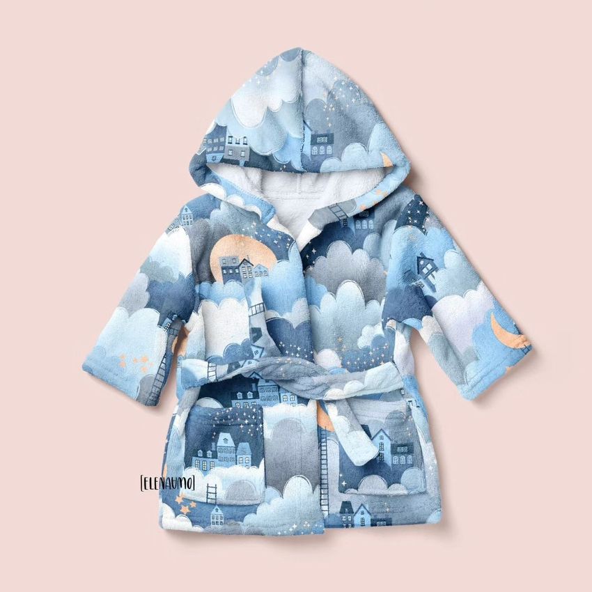 Baby bath dressing gown mockup featuring a hooded robe with a whimsical blue and white cloud and house pattern on a pale background.