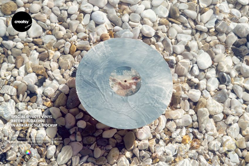 Vinyl record floating on clear Adriatic sea water, surrounded by light-colored pebbles, top view mockup scene.