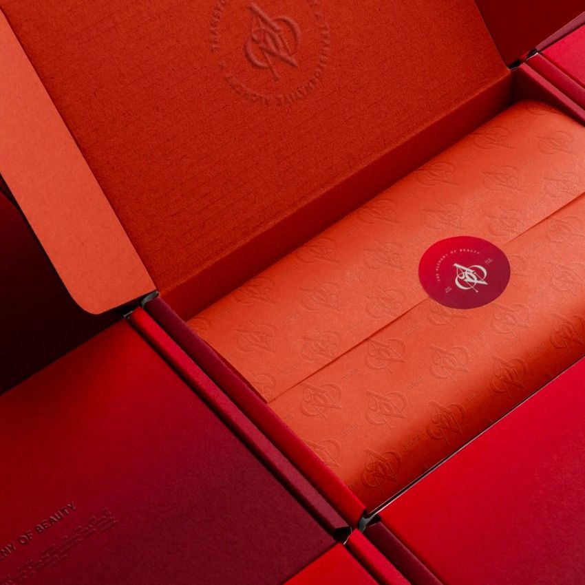 Mailing box mockup featuring an open red box with orange tissue paper inside, sealed with a circular red sticker.