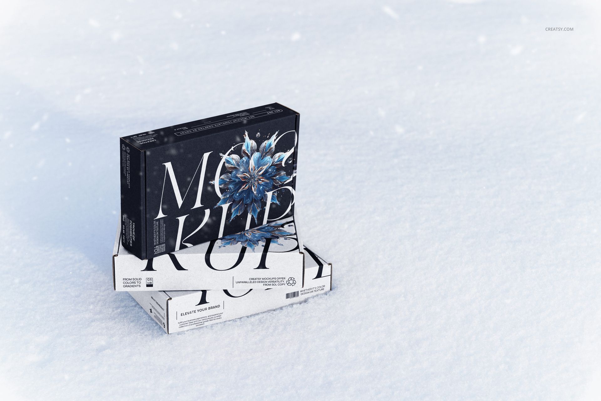 Two mailing box mockups, one dark with a blue flower and one white, arranged on snow in a winter scene, front view.