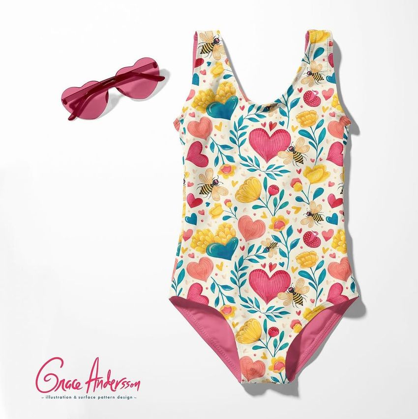 Baby swimsuit mockup featuring a colorful heart and bee pattern, shown flat on a white background with pink sunglasses.