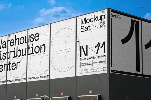 Front view of a warehouse distribution center building with large white advertising mockup panels and bold black text.
