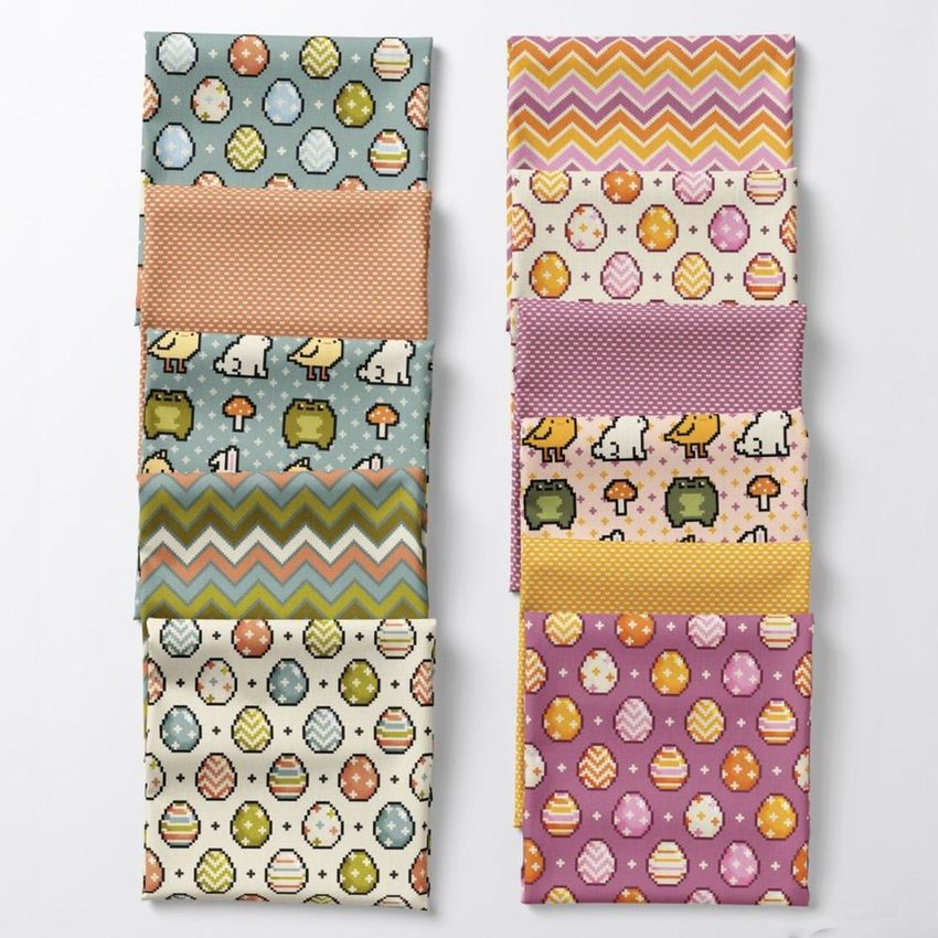 Folded fabrics mockup featuring colorful Easter-themed patterns with eggs, chicks, and zigzag designs arranged in two columns.
