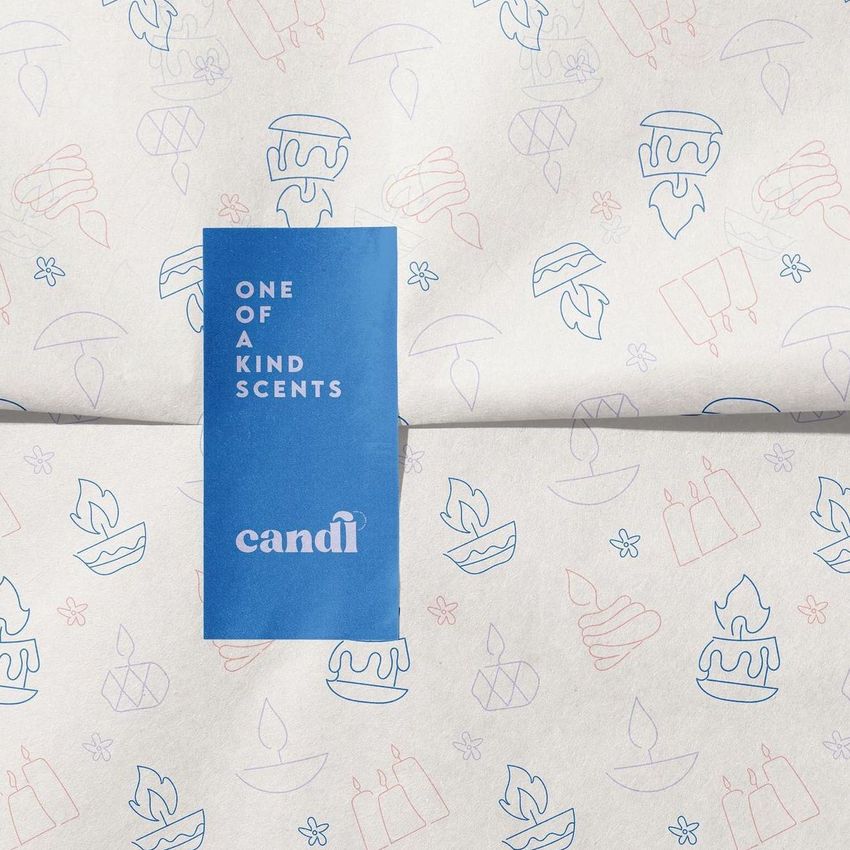 Wrapping paper mockup featuring a blue rectangular sticker with readable text and outlined candle-themed illustrations in pink and blue.