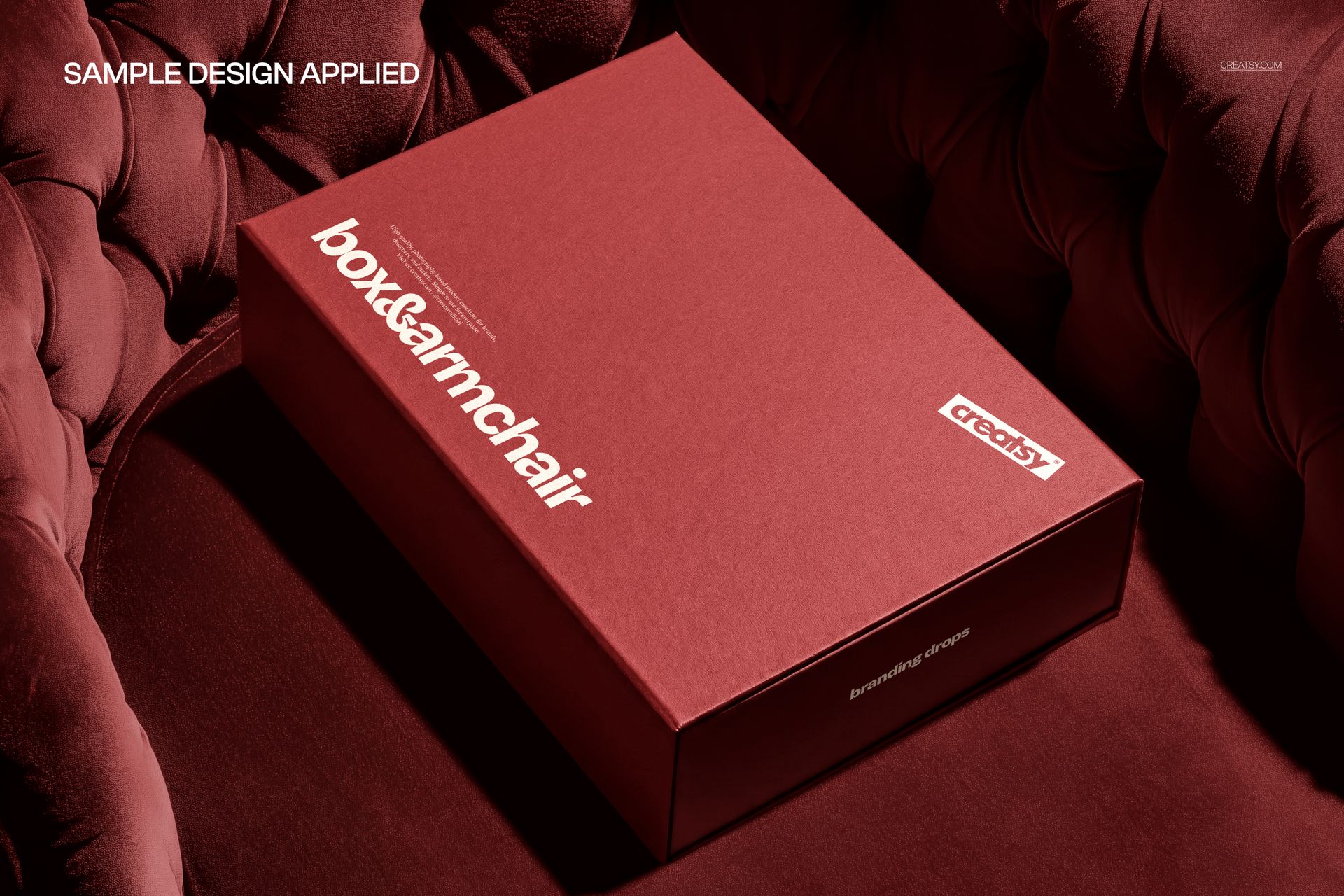 Red magnetic packaging box mockup resting on a tufted velvet chair, showing a perspective from above.