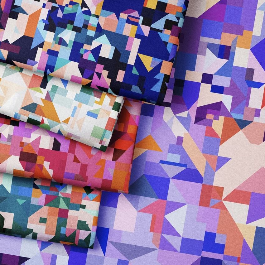 Folded fabrics mockup featuring geometric patterns in vibrant purples, blues, reds, and pastel tones, arranged on a matching patterned surface.