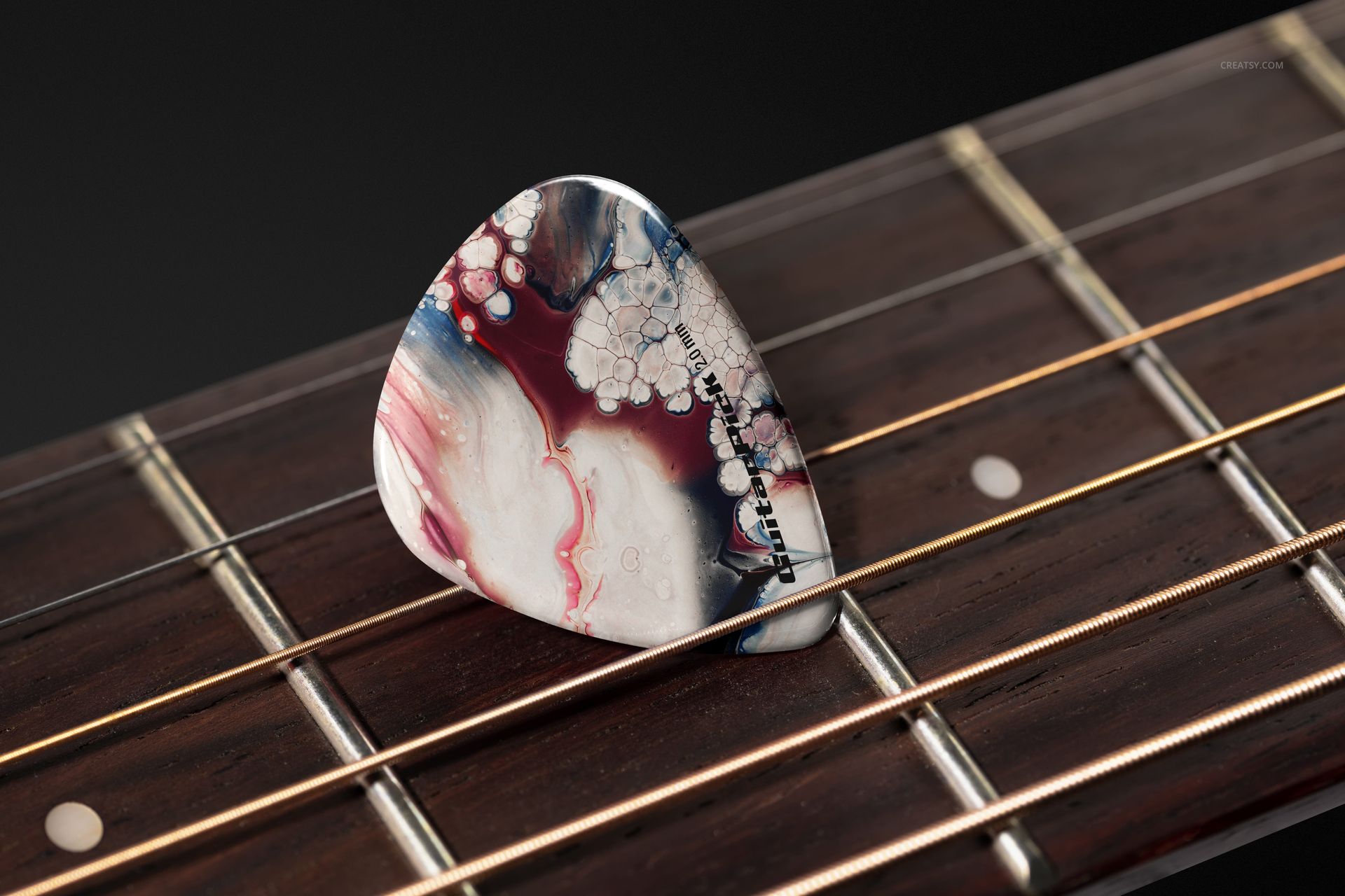 Guitar pick featuring a blend of red, blue, and white patterns placed on guitar strings in a PSD mockup scene.