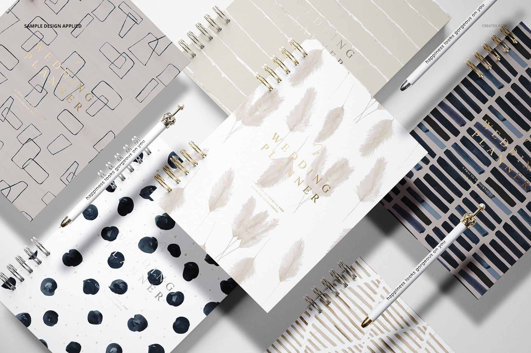 PSD mockup set showing multiple stationery planners with different cover patterns, displayed in a flat lay arrangement.