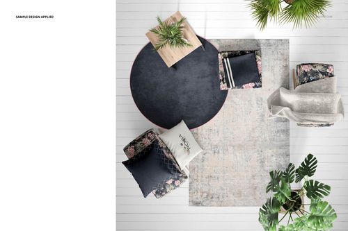 Interior textiles PSD mockup showing a round rug, assorted cushions, a blanket, and potted plants on a light floor.