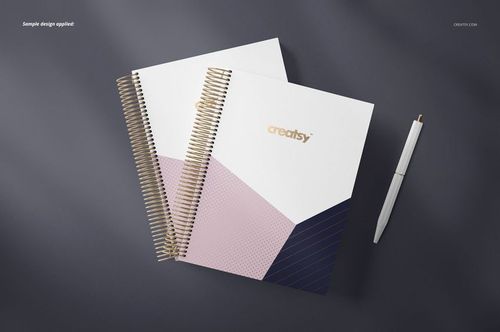 Coil binding planner mockup with two spiral notebooks featuring geometric covers in white, pink, and navy on a dark surface.