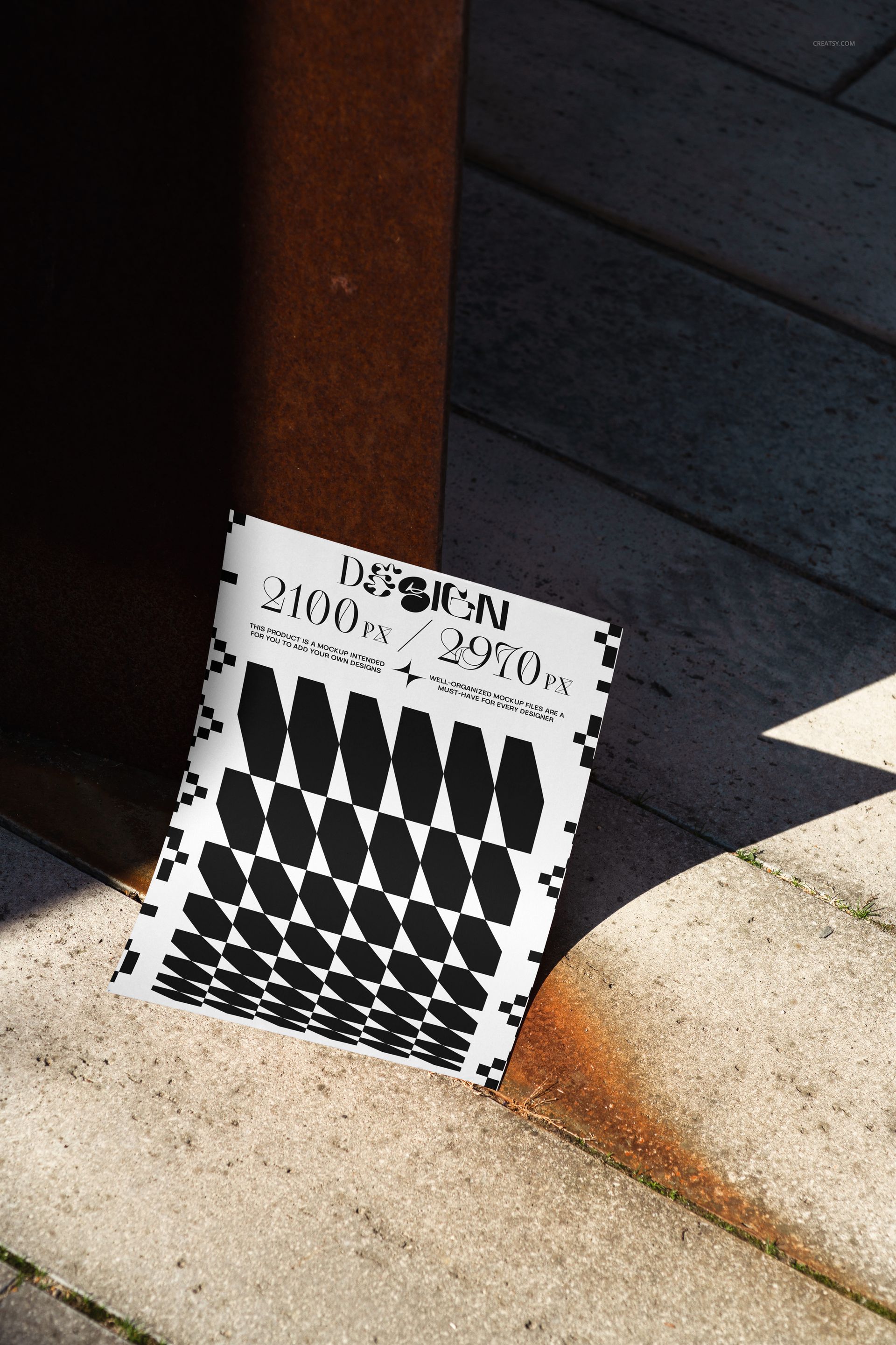 PSD mockup of a modern poster with abstract black and white design, resting on light stone tiles beside rusted metal.