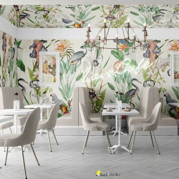 Cafe interior wallpaper mockup showing a bright space with botanical wall patterns, white tables, beige chairs, and a chandelier.