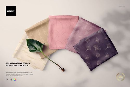 PSD mockup showing five silk scarves neatly folded in beige, pink, and purple hues on a plain background.