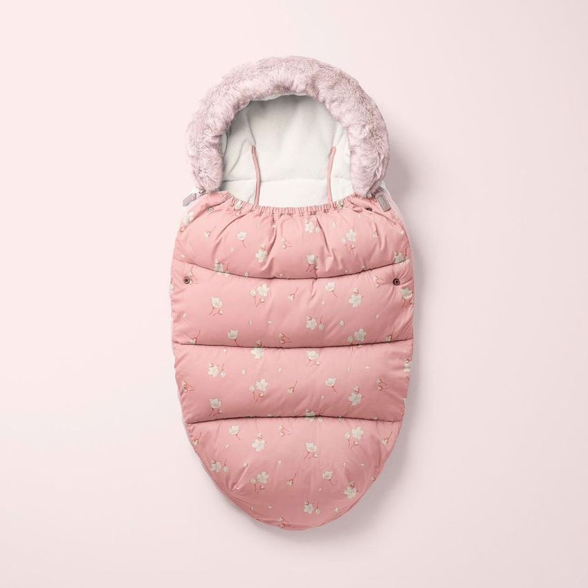 Footmuff mockup featuring a pink, padded baby sleeping bag with a cherry blossom pattern and faux fur trim, shown on a light pink background.