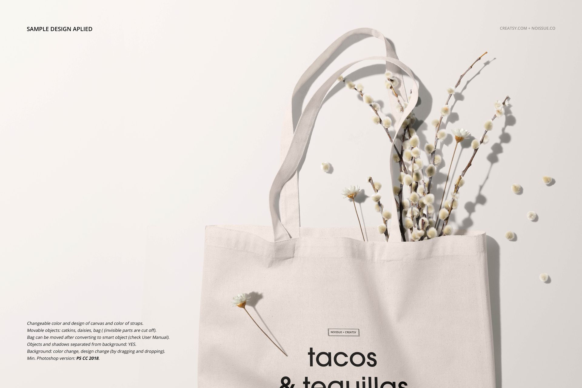 PSD mockup of a canvas tote bag featuring simple black lettering and decorative white flowers, shot from above.