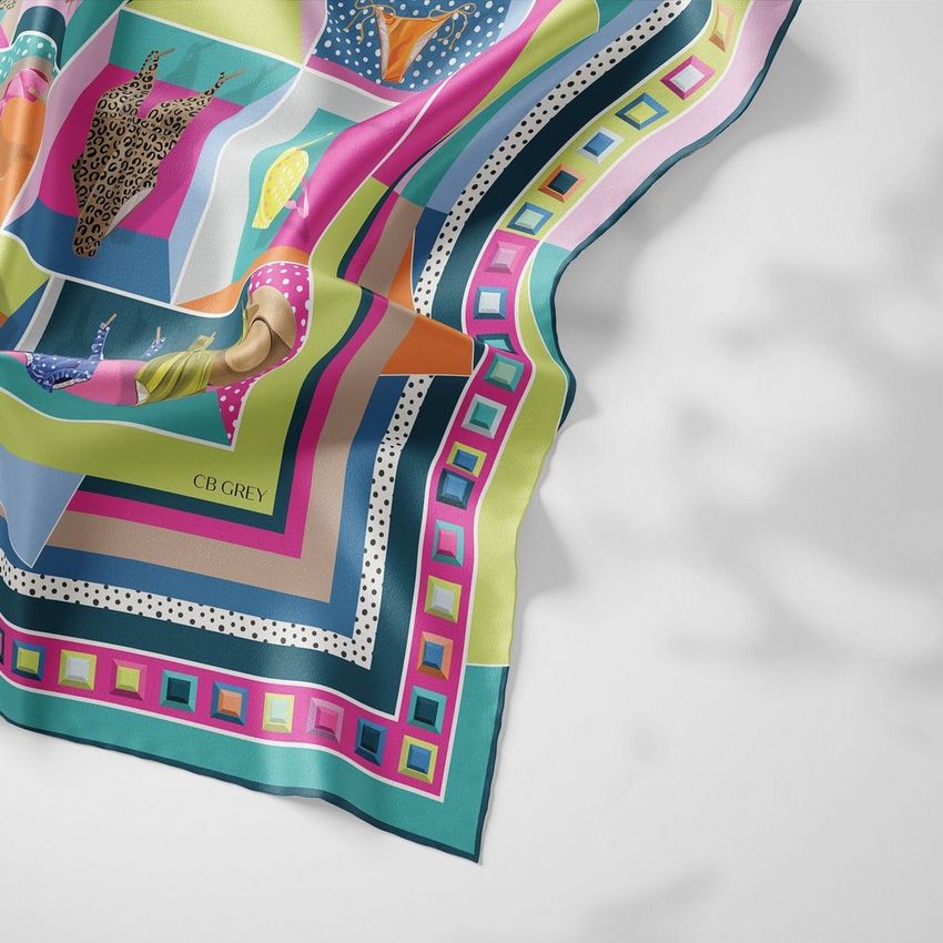 Silk scarf mockup showing a closeup of a colorful patterned fabric with geometric shapes and stylized figures on a light surface.