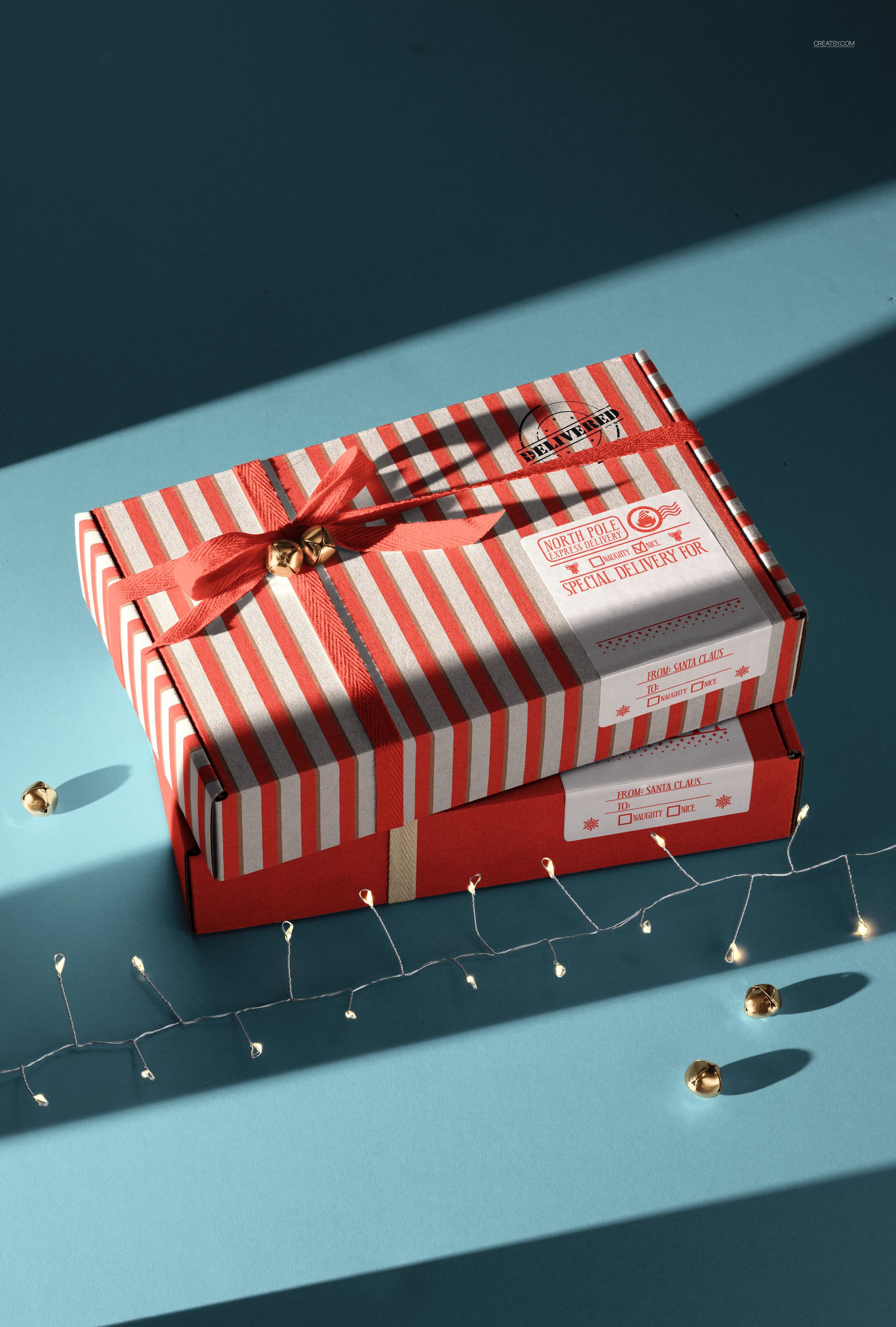 Christmas decor PSD mockup featuring wrapped presents with red and white stripes, ribbon, and gold bells on a blue surface.