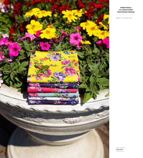 PSD mockup showing stacked patterned fabrics in various colors on a stone planter, set in an outdoor floral garden scene.