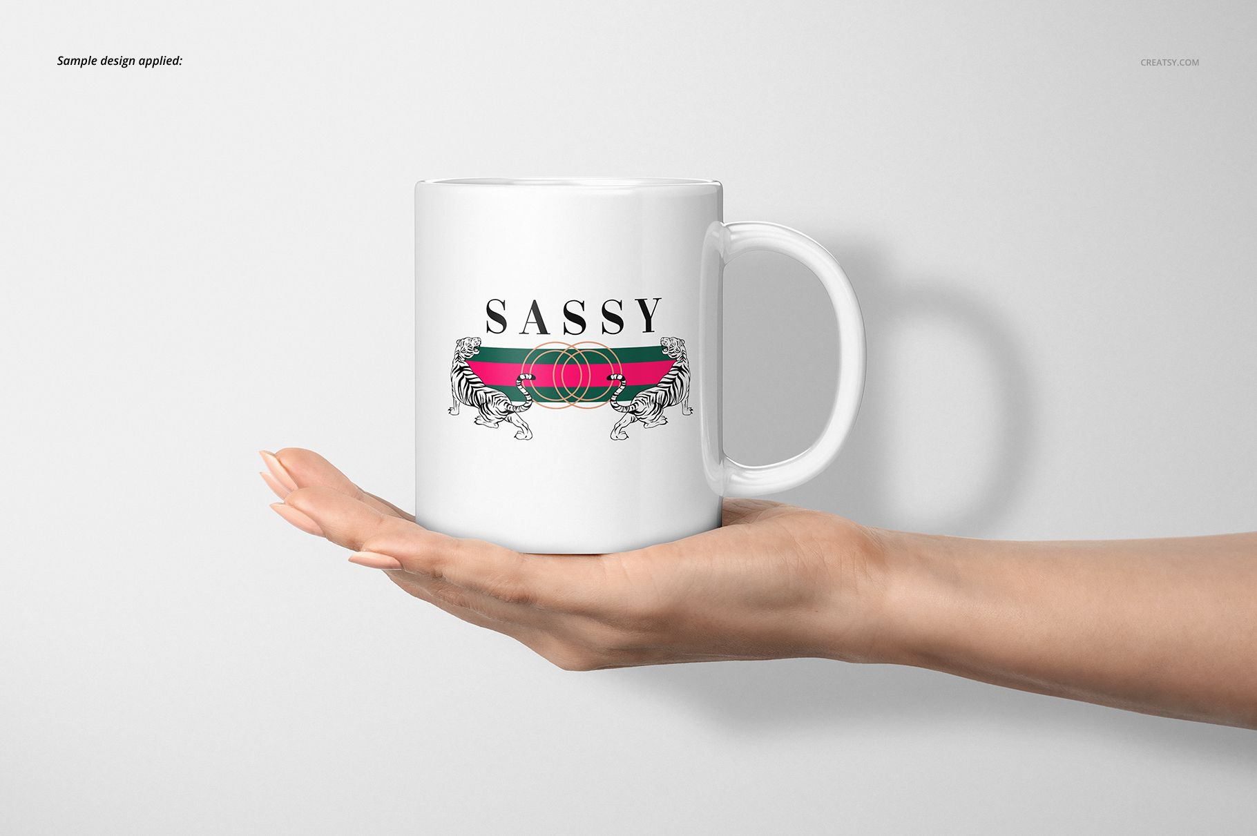 White ceramic 11oz mug with a bold graphic design, held in a hand against a plain light background, front view.