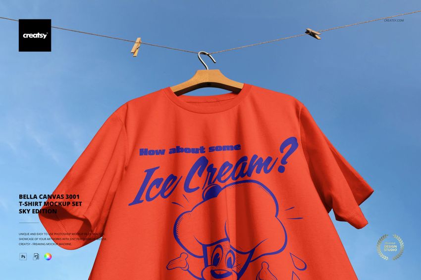 Red Bella Canvas t-shirt mockup displayed outdoors on a hanger, featuring bold blue artwork and sky background.