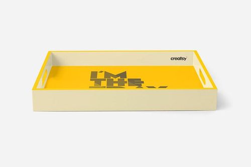 Mockup of a rectangular tray with cutout handles, cream outer edges, and a yellow interior with graphic text design.