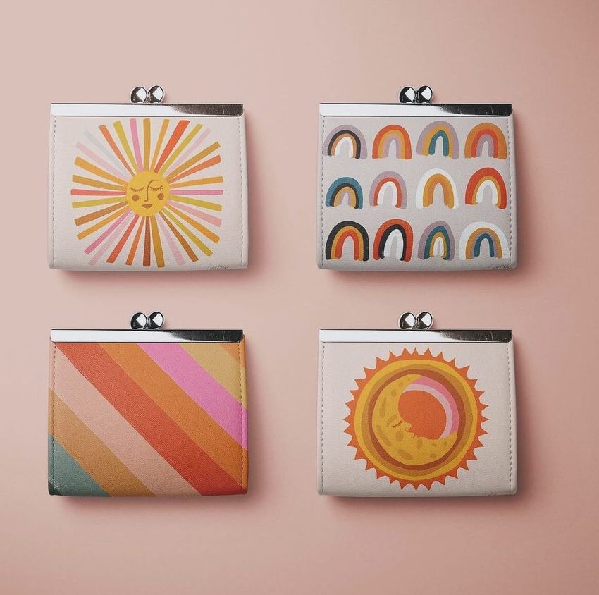 Leather wallet purse mockup featuring four purses with retro-inspired sun, rainbow, and stripe designs on a pale pink background.