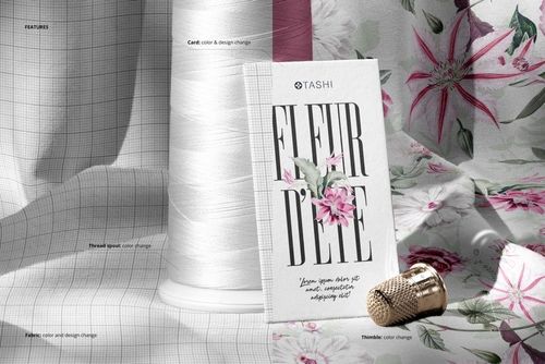 PSD mockup showing a thread spool, decorative card, and thimble arranged on soft floral jersey textile surface.