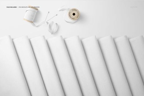 PSD mockup showing multiple folded fabric sections in white, accompanied by sewing accessories in a minimalist scene.