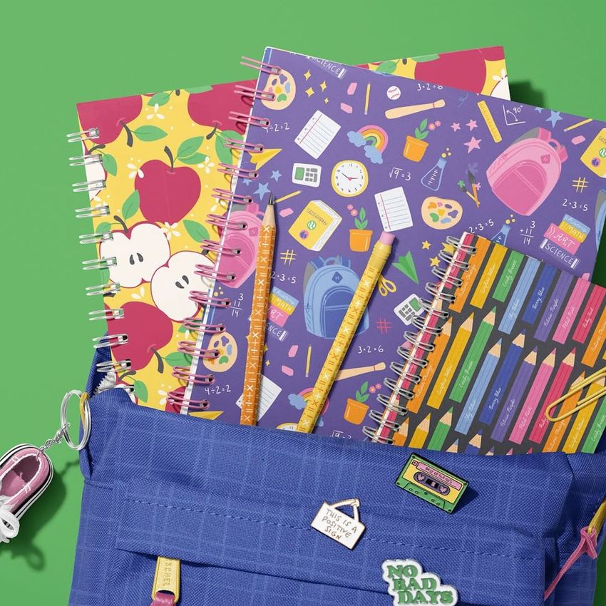 School backpack mockup with spiral notebooks featuring colorful patterns, pencils, and pins on a bright green background.