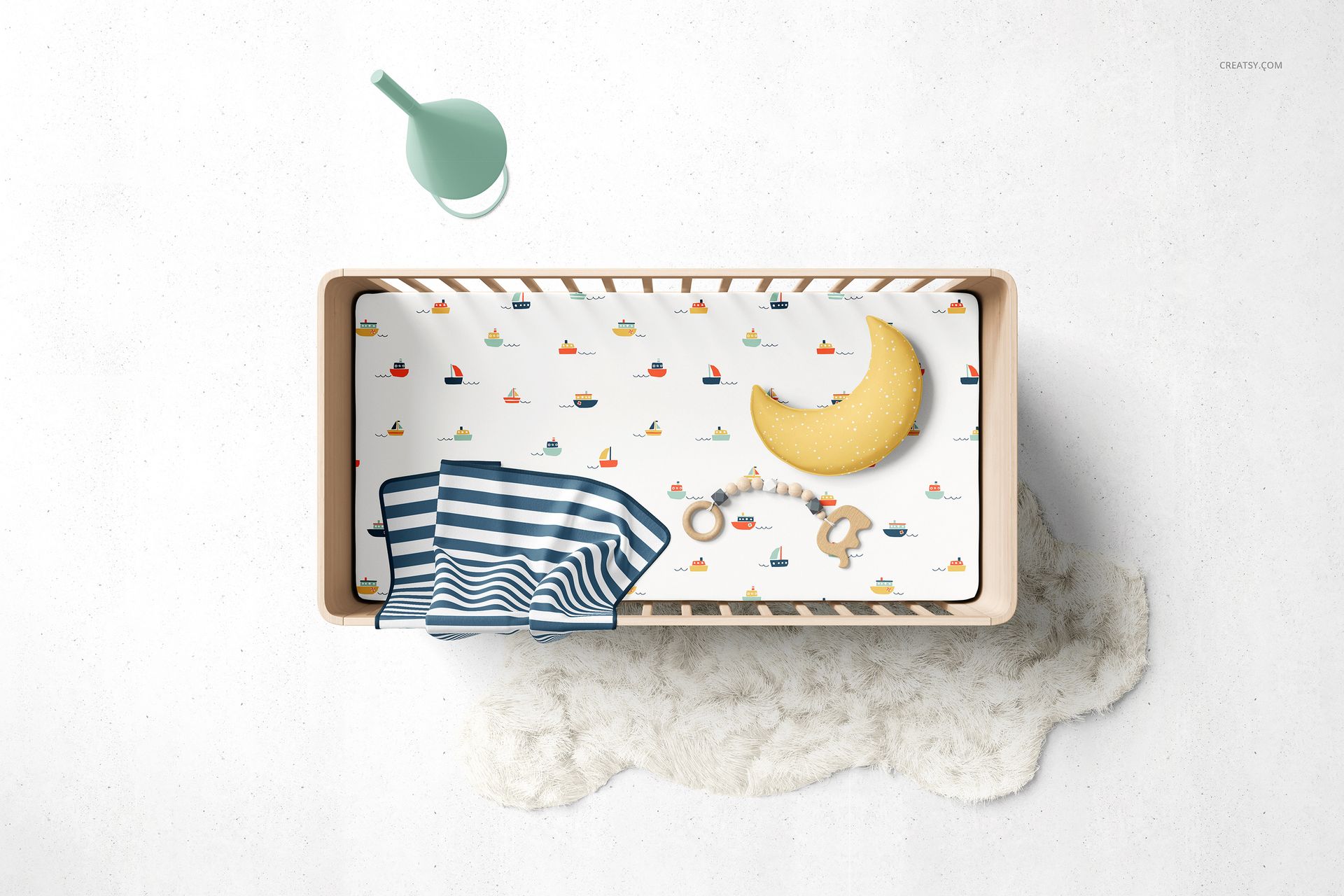 Top view of a fitted crib sheet mockup in a wooden crib, featuring a playful boat pattern and soft accessories.