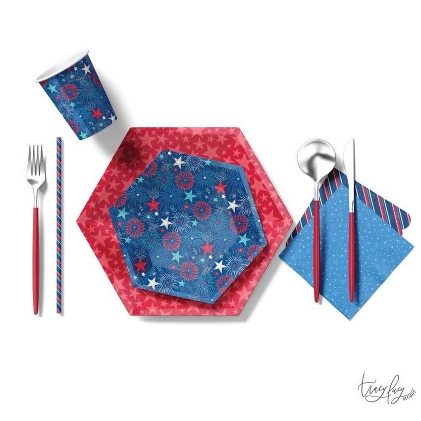 Party supplies mockup featuring red and blue plates with star and firework patterns, matching cup, napkin, and cutlery on white background.