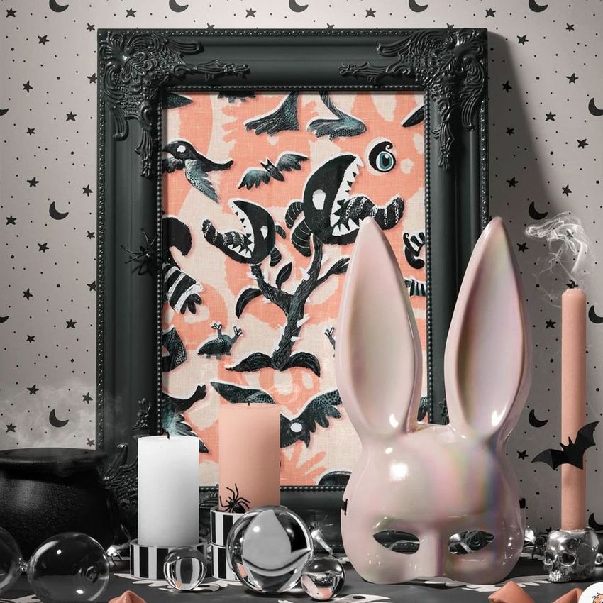 Halloween picture frame mockup featuring a spooky art print with bats and eerie shapes, surrounded by themed props and candles.