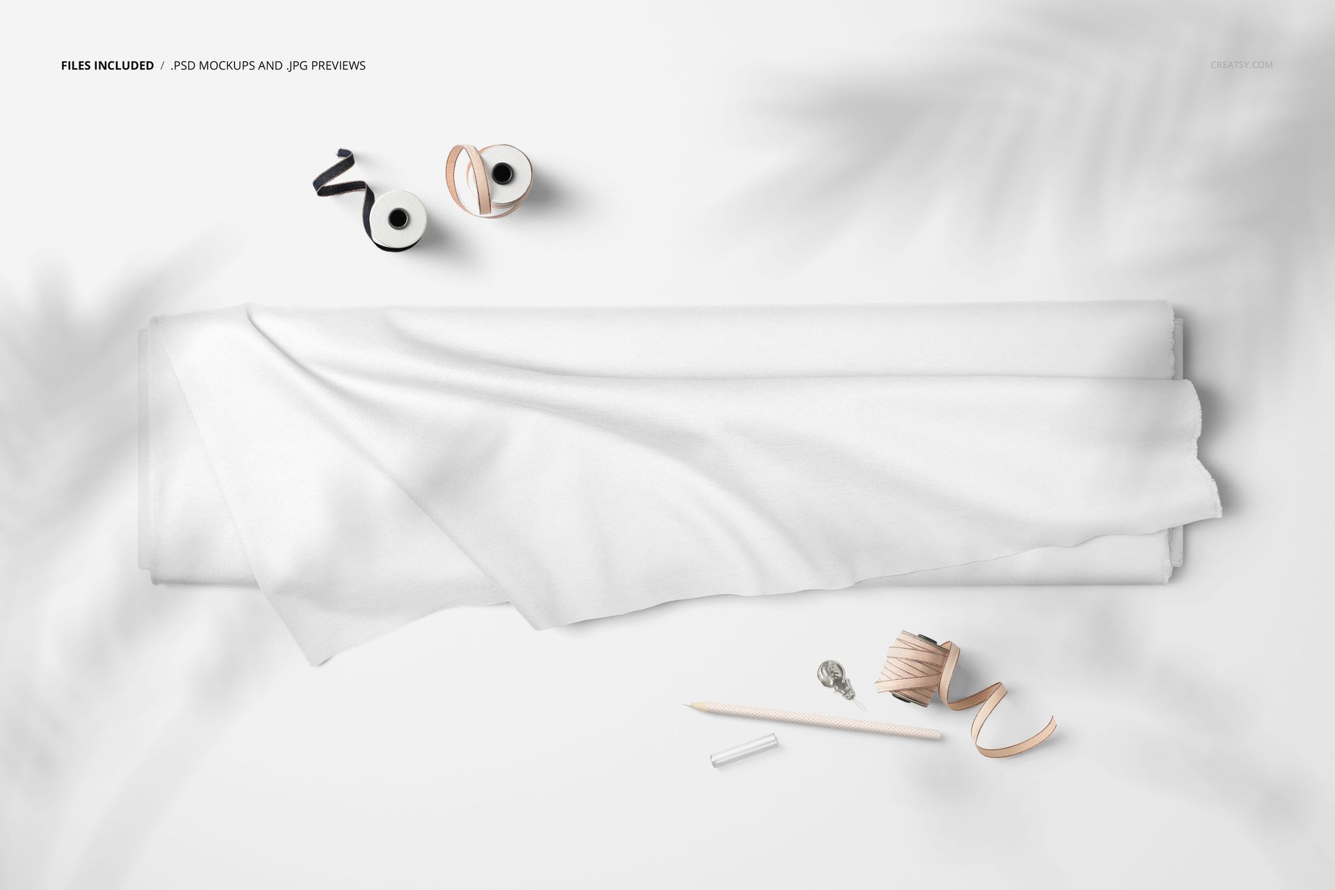 Top view of a fabric bolt mockup with white cloth draped, surrounded by sewing accessories on a light surface.