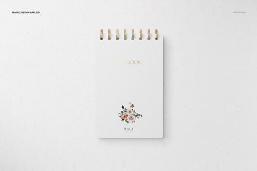 Front view of a spiral-bound stationery notebook mockup with a white cover, gold text, and floral illustration.