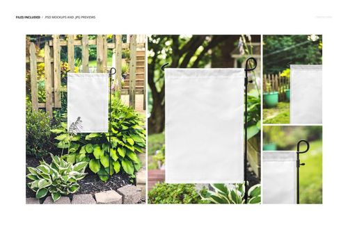 Blank yard flag mockup on a stand in a lush garden with wooden fence and various leafy plants in the background.