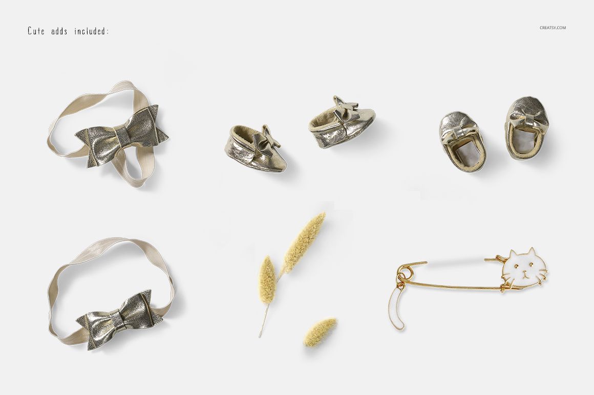Baby dress mockup accessories including gold shoes, ribbon bows, dried flowers, and a cat-shaped safety pin on a white background.